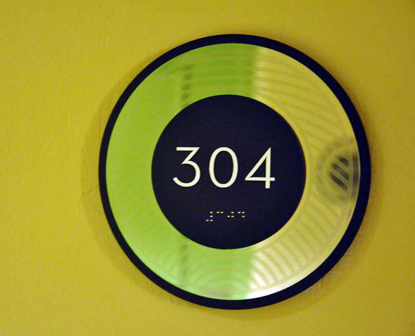 Guestroom signage. Clear varnish patterns were screenprinted on to lasercut and mirror polished stainless. The front and back discs are laser cut and painted a dark bronze metallic. The patterns were to be visual interpretations of the elements - earth, fire, air, water. 