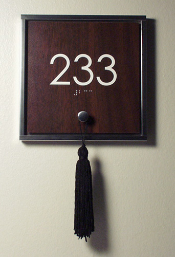Mirror polished frame with wood panel insert. Clevis pin at bottom holds tassle. 