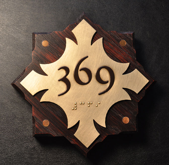 One of nine variations on the guest room sign. There were (3) different brass plates and (3) different stained white oak backers. Edges were stop chamfered. Brass discs were set flush in oak.