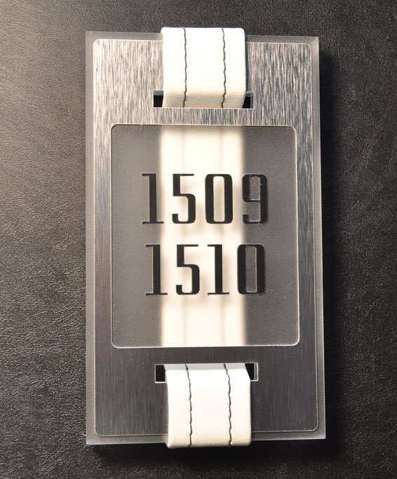 The sign is a matched metal plate and frosted acrylic block. The white belting was custom stitched and laced through the plates. This hotel was LEED Gold certified. Index also provided a sign program describing the LEED features for additional LEED points.